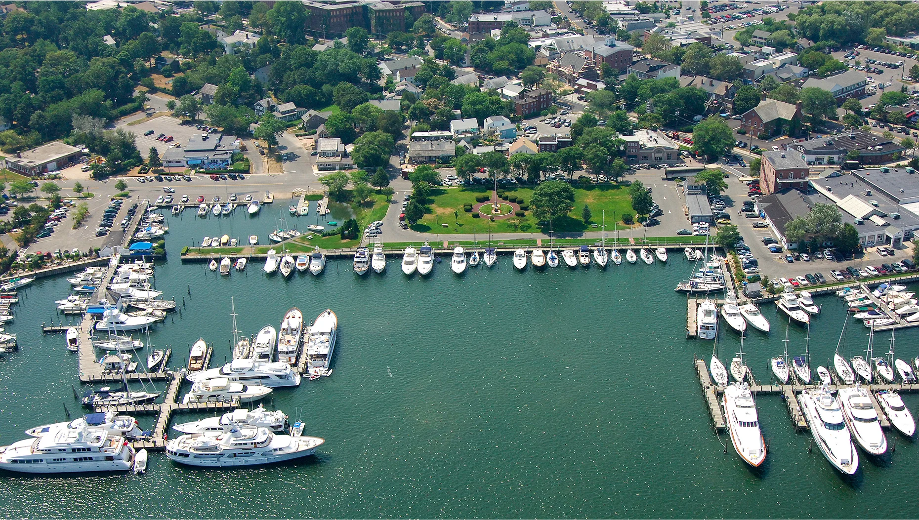 Aerial view of Sag Harbor marina with luxury superyachts docked along the Hamptons waterfront, New York