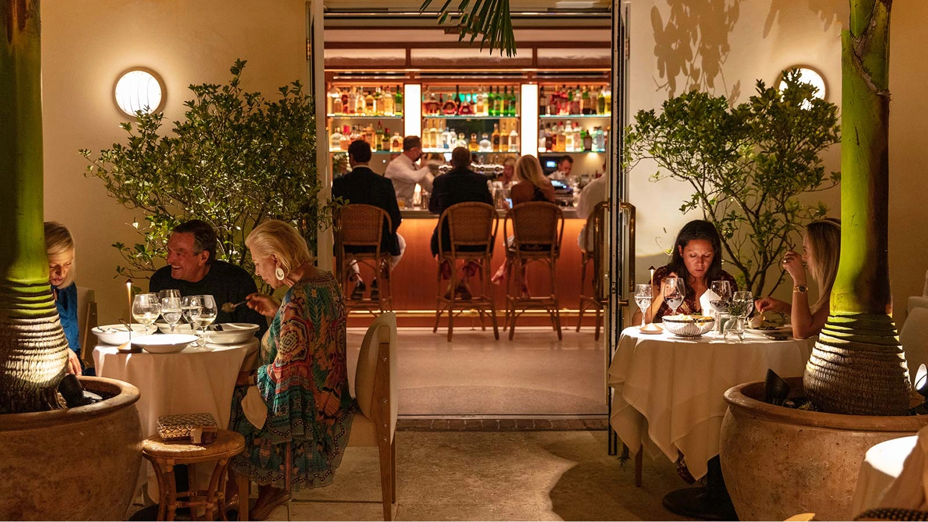 Chic French bistro interior at Le Bilboquet on Worth Avenue, featuring romantic lighting and floral arrangements.