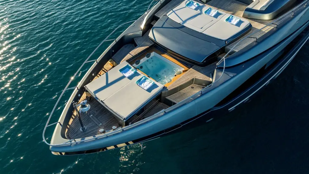 Aerial view of 2024 Riva 110 Dolcevita TAKU foredeck featuring custom pool with yellow accent lighting, white sunpads with blue striped pillows, and teak decking