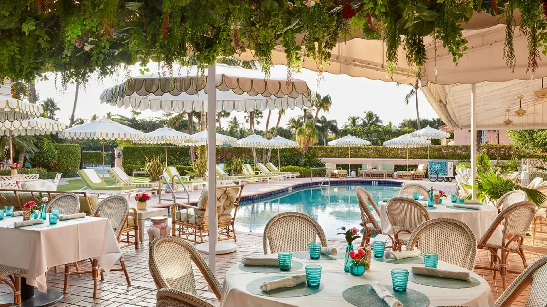 Al fresco poolside dining at Swifty’s at The Colony Hotel, featuring iconic pink decor and lush greenery.