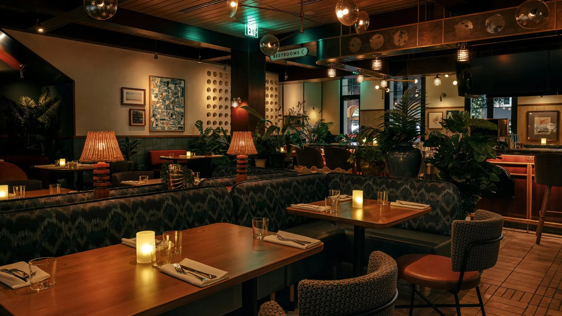 Warmly lit dining room at Earls on Las Olas with booth seating, candlelit tables and tropical plants