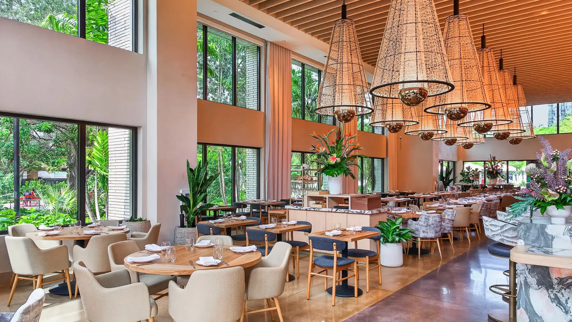Bright dining room at Sweetwaters with woven pendant lights, floor-to-ceiling windows and garden views