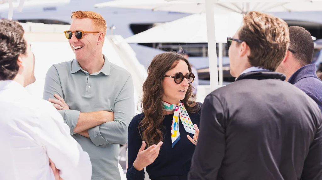 Independent yacht brokers talking with clients under white umbrellas at a boat show